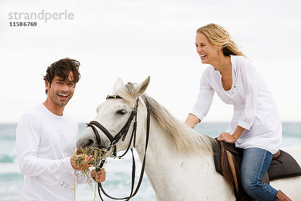 Mann und Frau mit Pferd am Strand