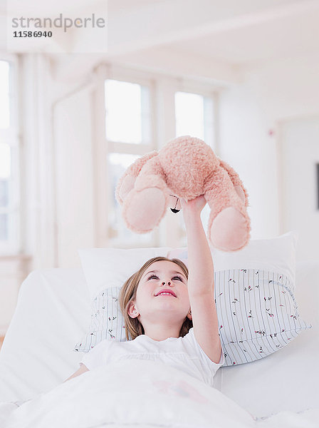 Mädchen im Bett spielt mit Teddybär