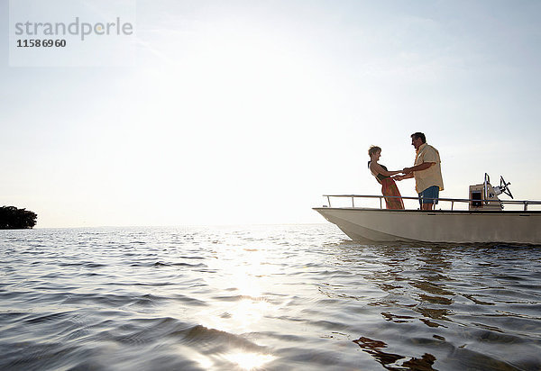 Älteres Ehepaar hält auf Motorboot Händchen
