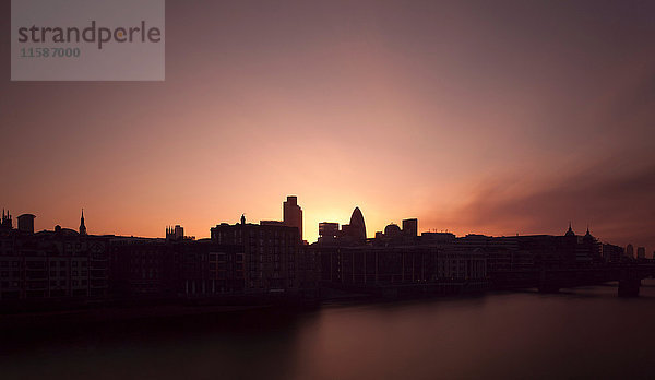Sonnenaufgang über städtischen Gebäuden am Fluss