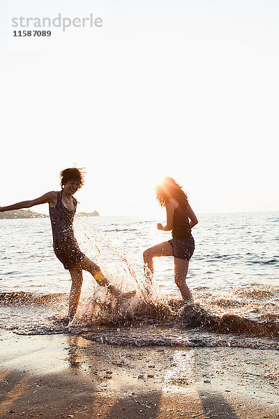 Frauen spielen in Wellen am Strand