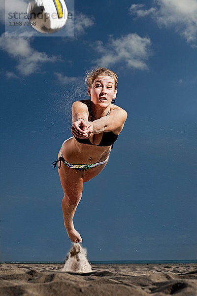 Junge Frau spielt Beach-Volleyball