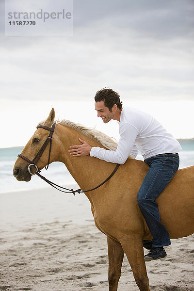 Mann reitet Pferd am Strand