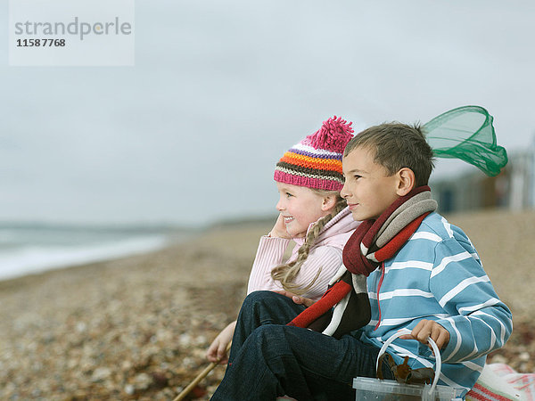 Junge und Mädchen am Strand mit Blick aufs Meer