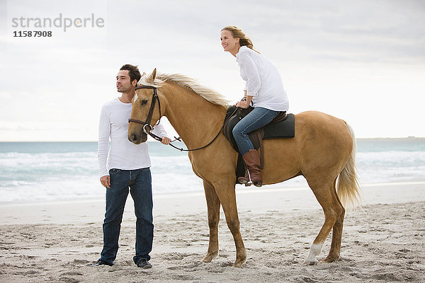 Mann und Frau mit Pferd am Strand