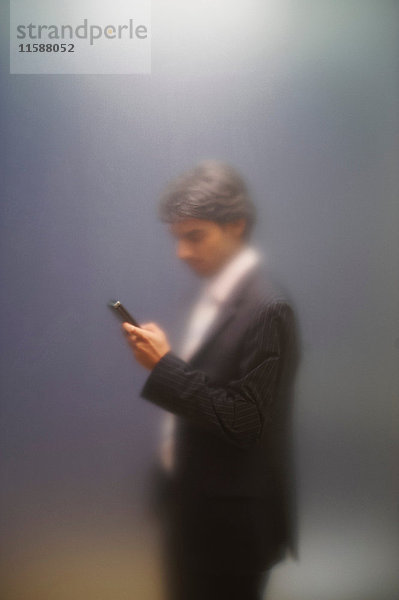 Mann mit Telefon hinter vereistem Bildschirm