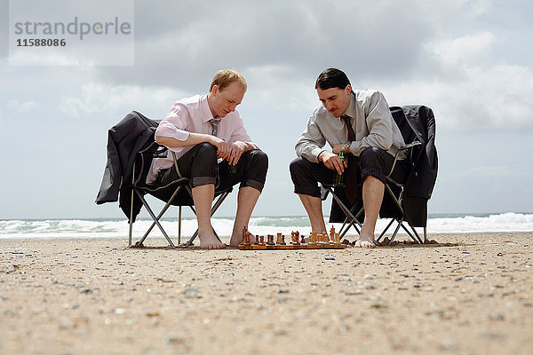Geschäftsleute spielen Schach am Strand
