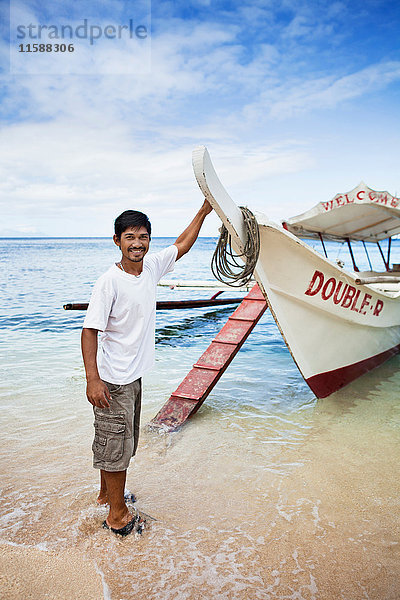 Mann mit Boot am tropischen Strand