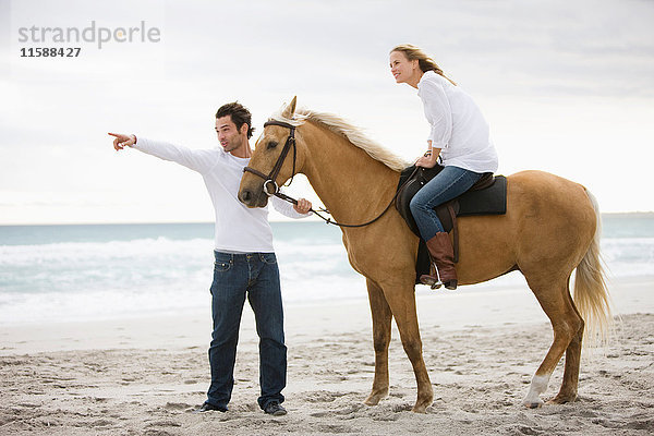 Mann und Frau mit Pferd am Strand