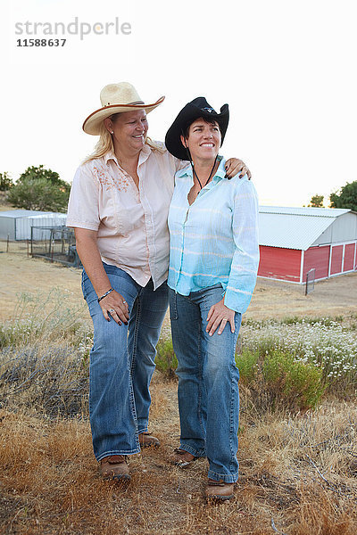 Reifes lesbisches Paar steht zusammen auf der Ranch und lächelt