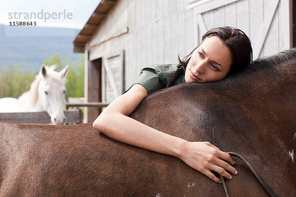 Frau  die sich auf ein Pferd stützt