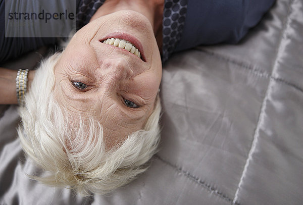 Seniorin entspannt auf dem Bett  lächelnd