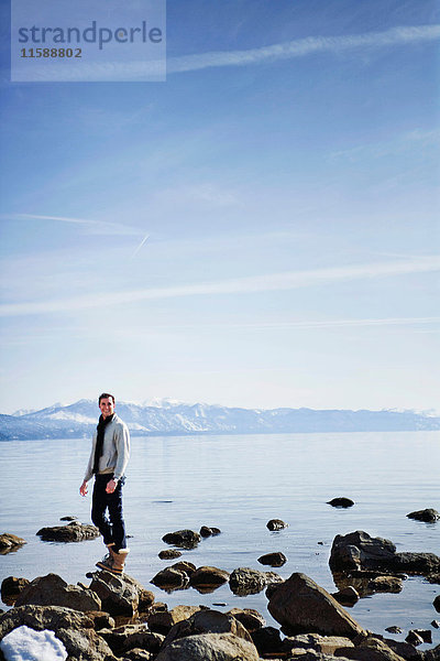 Mann steht auf Felsen in der Nähe des Sees