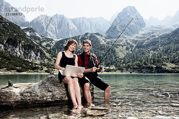 Paar fischen und Laptop benutzen am See