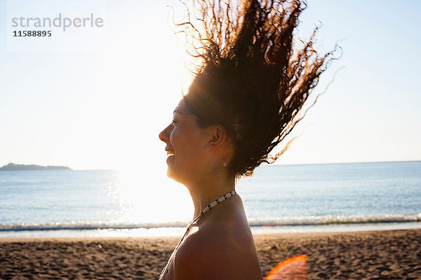 Frau spielt am Strand mit ihren Haaren