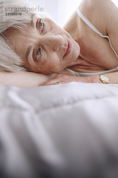 Seniorin entspannt auf dem Bett