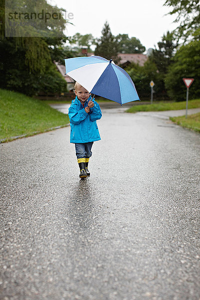 Kleinkind Junge mit Regenschirm auf der Strasse