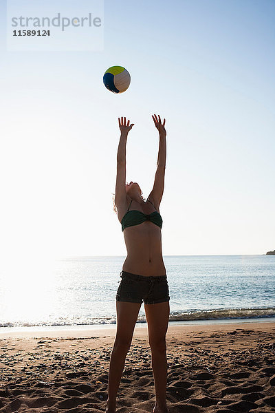 Frau spielt mit Volleyball am Strand