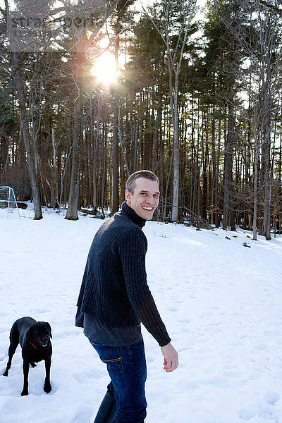 Mann mit Hund im Wald im Schnee