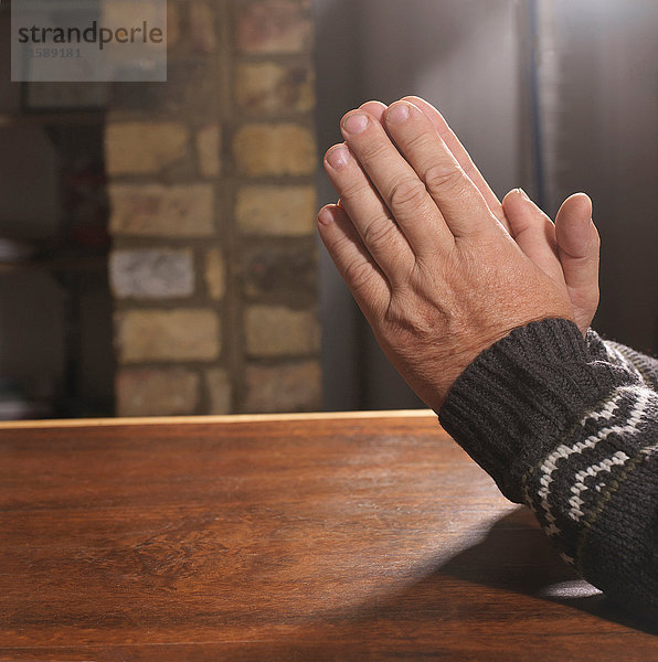 Älterer Mann mit zum Gebet ergriffenen Händen