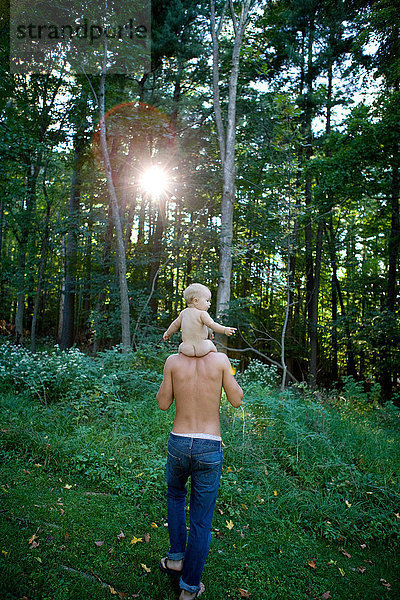 Vater trägt kleines Mädchen auf den Schultern im Wald