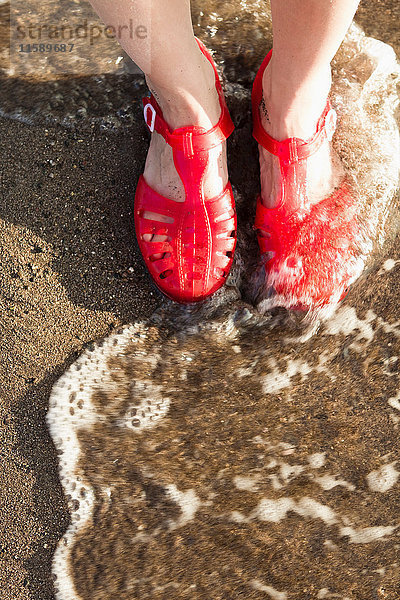 Frau mit Sandalen am Strand