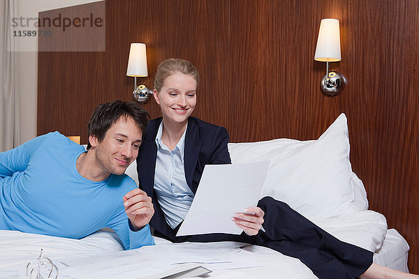 Paar im Hotelbett lesend  lachend