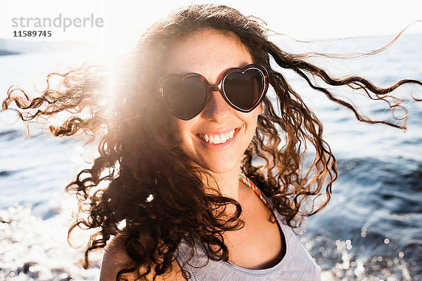 Lächelnde Frau mit Sonnenbrille am Strand