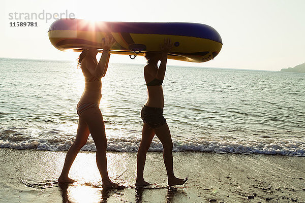 Frauen tragen Schlauchboot am Strand