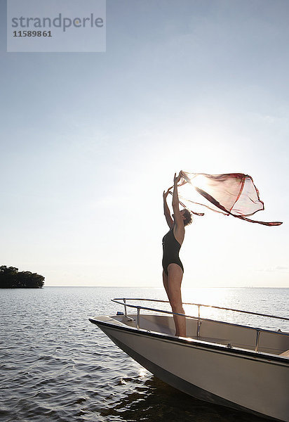 Ältere Frau hält Sarong in der Luft auf einem Motorboot
