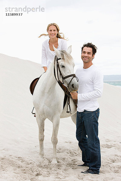 Frau und Mann mit Pferd am Strand