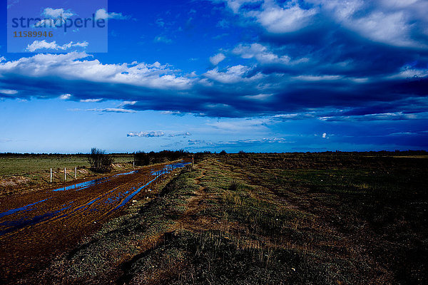 Schlammige Landstraße unter blauem Himmel