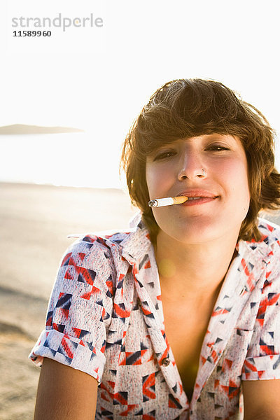 Frau raucht Zigarette am Strand