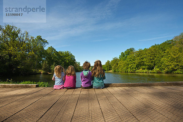 Kinder sitzen auf einem Holzdock im See