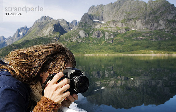 Frau beim Fotografieren in einer Berglandschaft