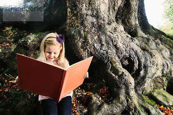 Junges Mädchen liest ein Buch in einem Waldgebiet