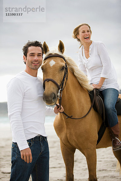 Mann und Frau mit Pferd am Strand