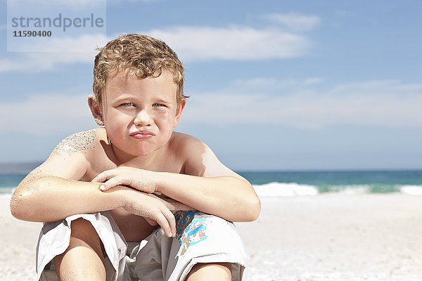 Junge sitzt am Strand