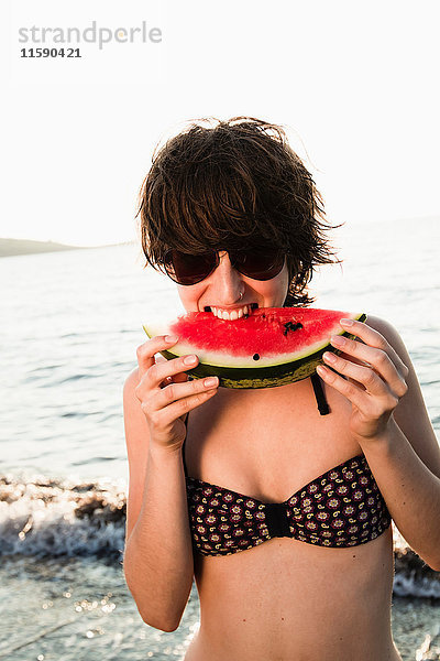 Frau isst Wassermelone am Strand