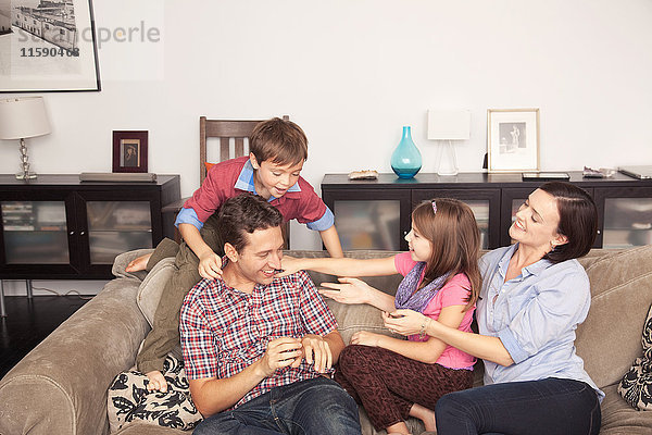 Vierköpfige Familie  die gemeinsam auf dem Sofa entspannen