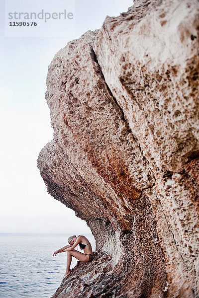 Frau  die auf den Felsen an Klippen sitzt