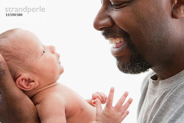 Lachender Vater sieht junges Baby an