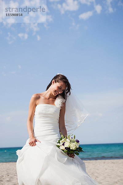 Braut hält den Brautstrauss am Strand
