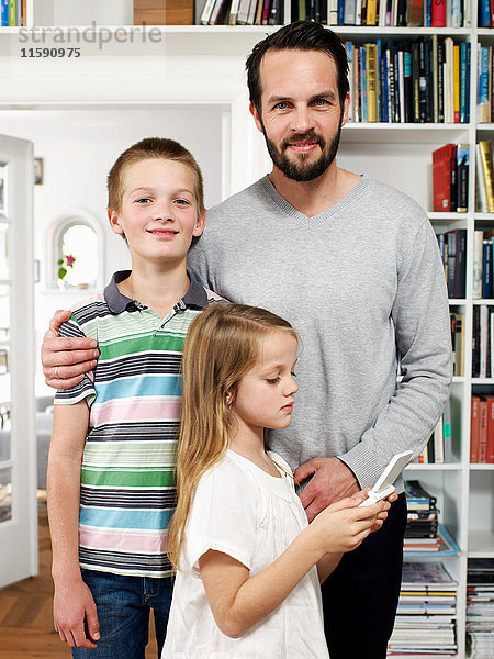 Vater und Familie stehen zusammen im Wohnzimmer  Porträt