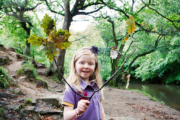 Mädchen hält einen Eichenast in einem Waldgebiet