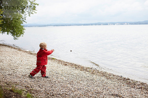 Junge wirft Steine in See