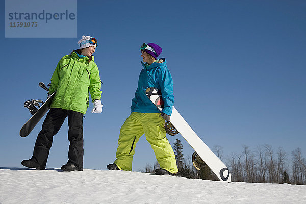 Zwei Frauen tragen Snowboards