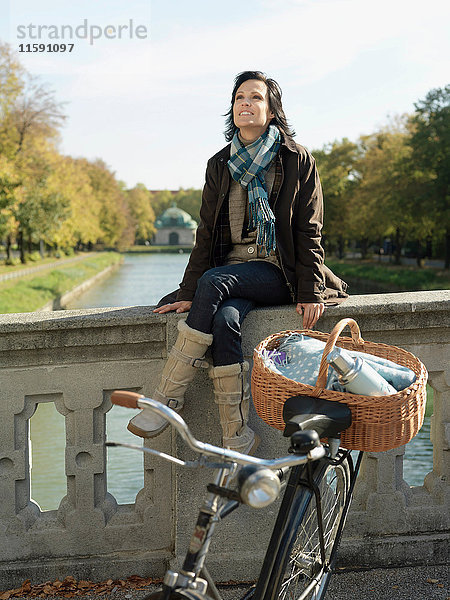 Frau sitzt im Herbst auf der Flussbrücke