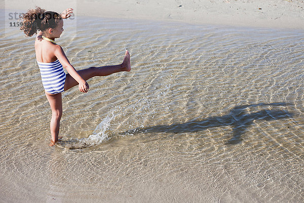junges Mädchen spielt am Strand im Wasser