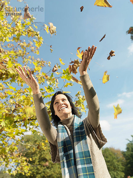 Frau mit Herbstlaub in der Luft